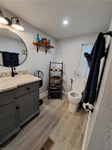 Bathroom with hardwood / wood-style flooring, toilet, and vanity