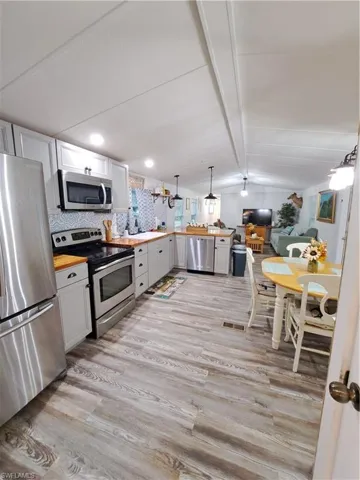 Kitchen featuring light hardwood / wood-style flooring, backsplash, stove, refrigerator, and butcher block countertops