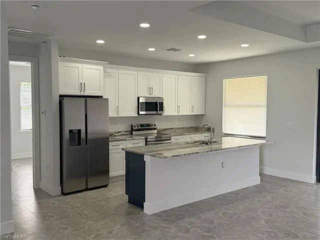 Kitchen with white cabinetry, visible vents, a center island with sink, and appliances with stainless steel finishes