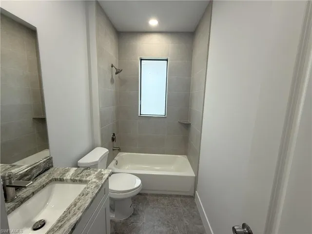 Full bath featuring baseboards, toilet, vanity, and washtub / shower combination