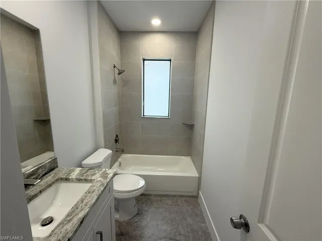 Bathroom featuring baseboards, toilet, shower / tub combination, and vanity