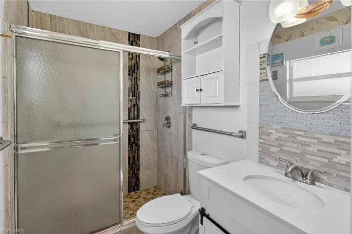Bathroom featuring vanity, a stall shower, and backsplash