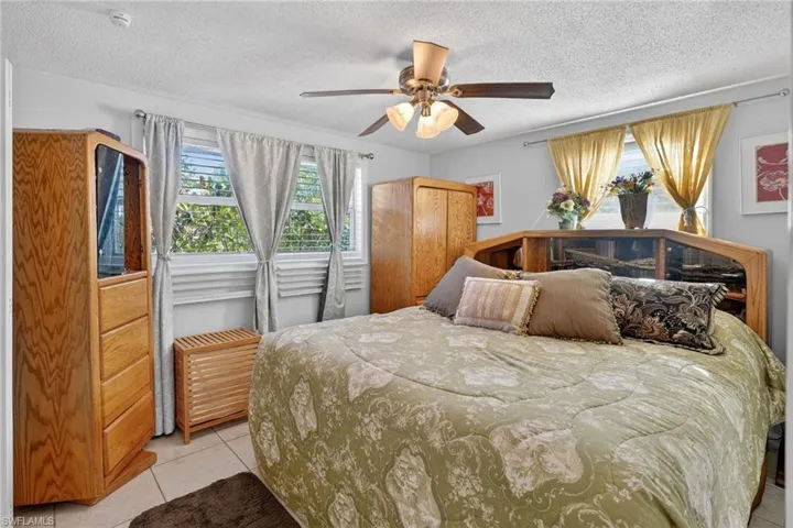 Bedroom with light tile patterned floors, a ceiling fan, and a textured ceiling