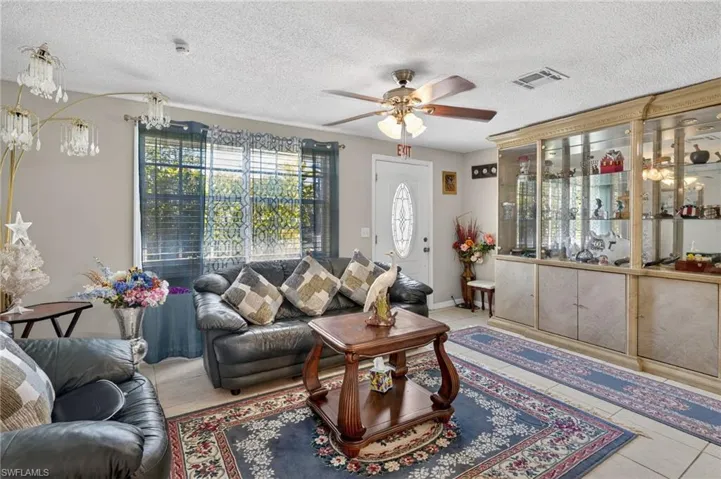Living room with ceiling fan, tile patterned floors, and a textured ceiling