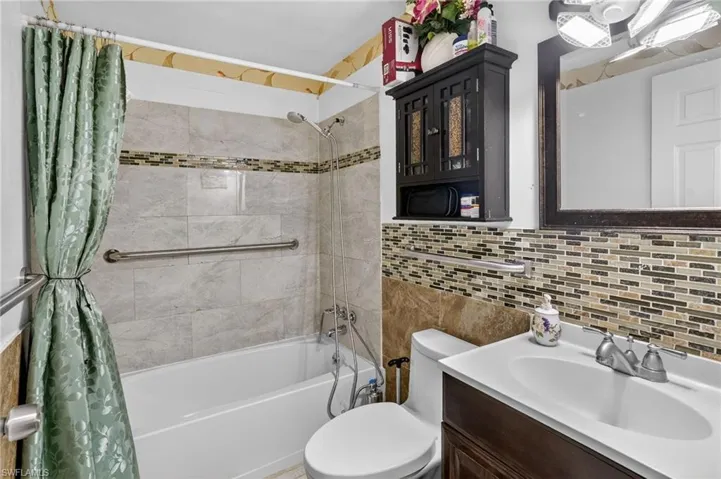 Bathroom with vanity, shower / bath combination with curtain, and tile walls