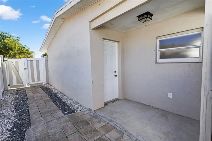 View of exterior entry featuring a gate and stucco siding