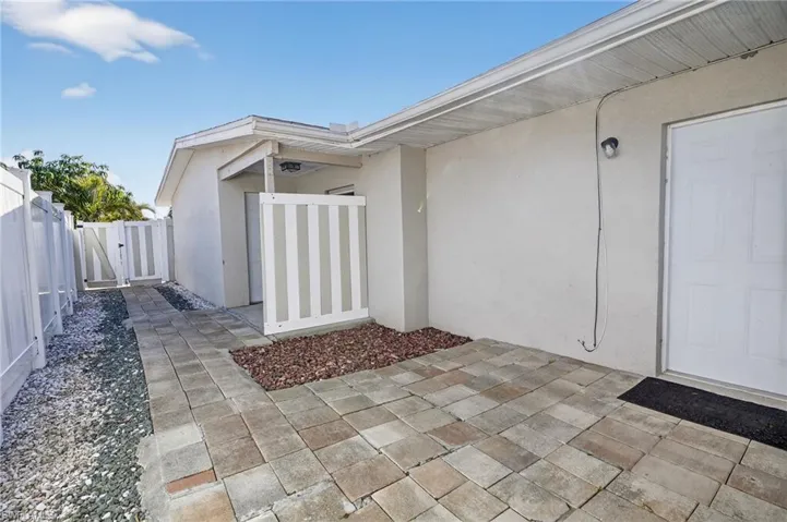 Doorway to property featuring stucco siding and a gate