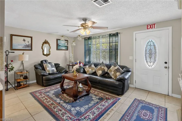 Living room featuring a ceiling fan, healthy amount of natural light, a textured ceiling, and light tile patterned floors