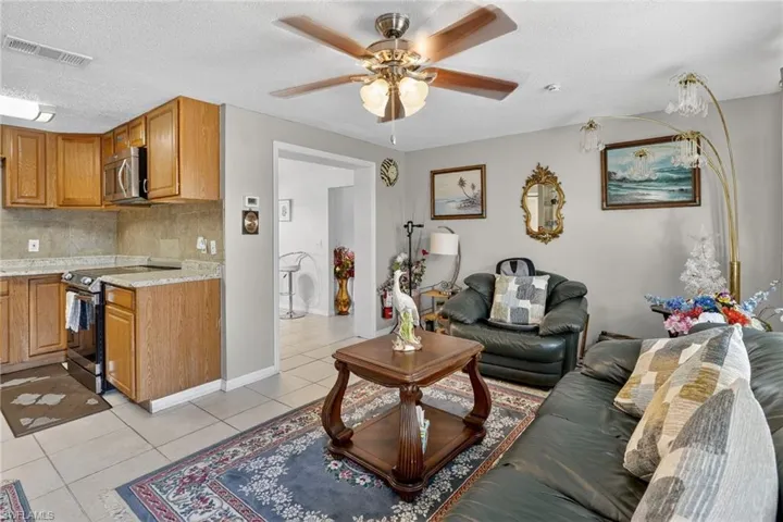 Living room with a textured ceiling, light tile patterned floors, and ceiling fan