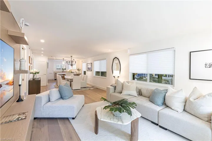 Living area featuring light wood-style floors, baseboards, a notable chandelier, and recessed lighting