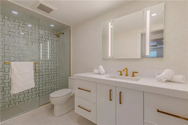 Full bath with toilet, vanity, visible vents, and a shower stall