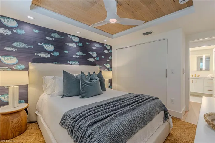 Bedroom with visible vents, a raised ceiling, wood ceiling, and wallpapered walls