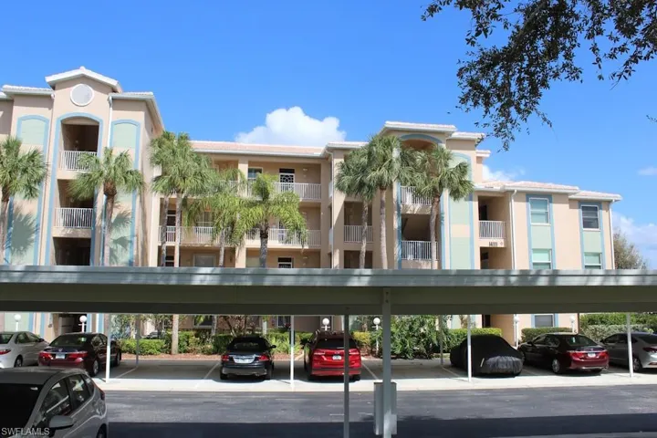 View of apartment building / complex featuring covered parking
