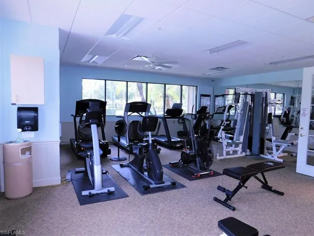 Exercise room with ceiling fan and a wainscoted wall