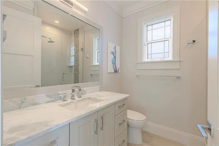 Bathroom featuring crown molding, a shower with door, vanity, and toilet