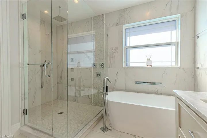 Bathroom featuring vanity, tile walls, and independent shower and bath