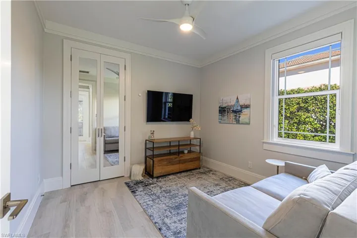 Living room with ceiling fan, light wood-type flooring, and ornamental molding