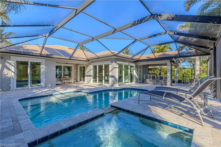 View of swimming pool with an in ground hot tub, a patio, and glass enclosure
