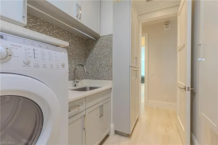 Laundry area with cabinets, washer / dryer, light hardwood / wood-style flooring, and sink