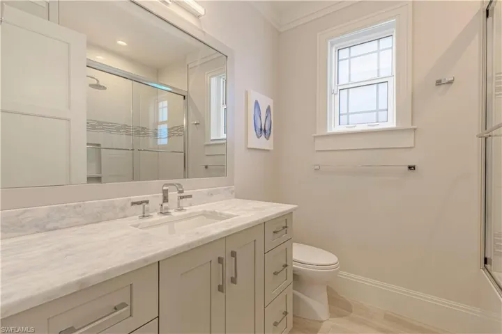 Bathroom with vanity, toilet, a shower with door, and ornamental molding