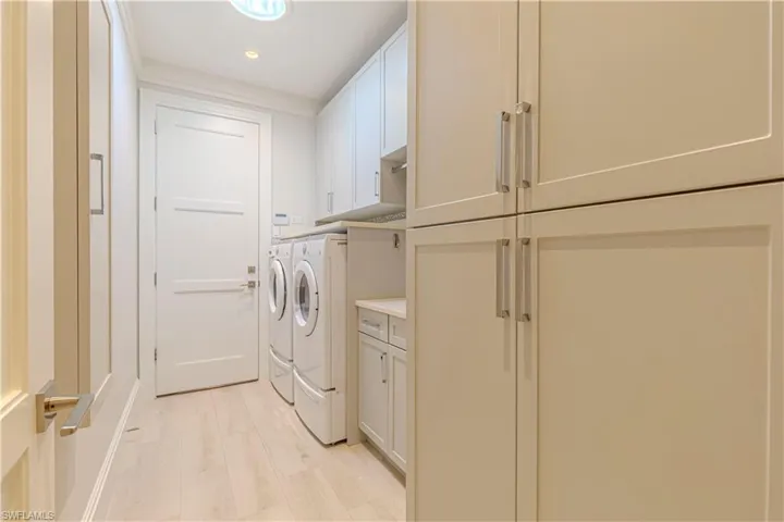 Clothes washing area featuring cabinets, separate washer and dryer, and light wood-type flooring