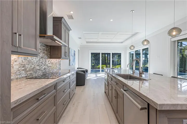 Kitchen with dishwasher, a large island with sink, black electric stovetop, wall chimney range hood, and sink