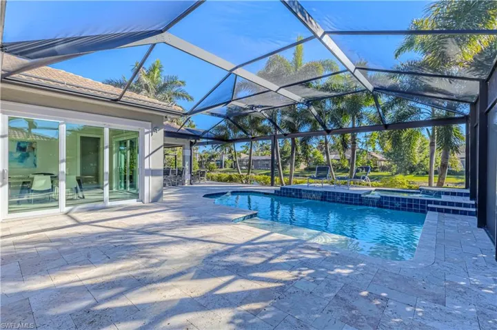 View of swimming pool with a patio area and glass enclosure