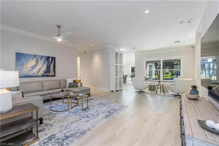 Living room with light wood-type flooring, ceiling fan, and crown molding