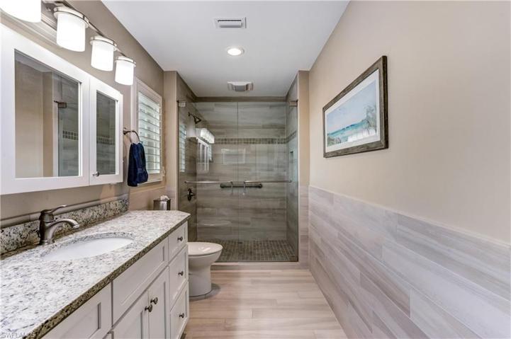 Main bath with custom tiled shower, glass shower doors, new vanity/lighting.