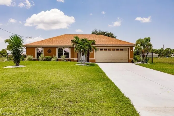 View of front facade featuring a front lawn and a garage