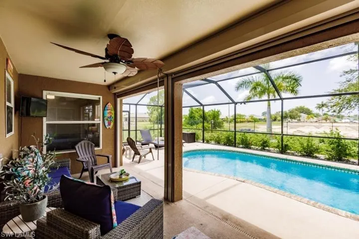 View of swimming pool featuring ceiling fan, a lanai, and a patio area