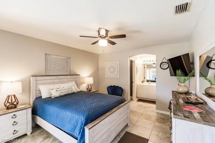 Bedroom with ensuite bath, ceiling fan, and light tile patterned floors