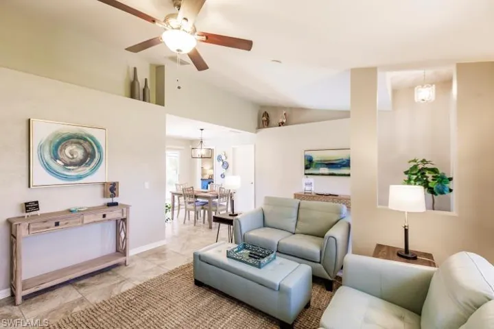 Living room featuring ceiling fan with notable chandelier and lofted ceiling