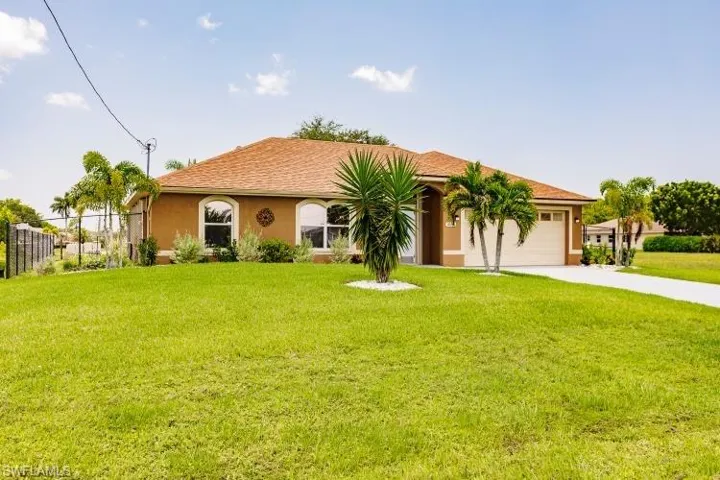 View of front of property featuring a garage and a front lawn