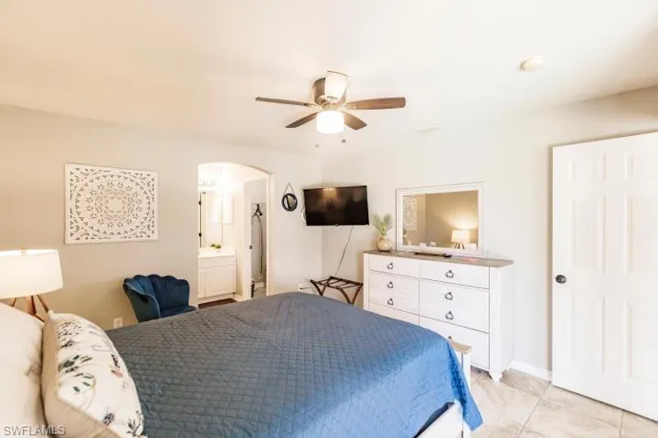 Bedroom with ceiling fan, ensuite bathroom, and light tile patterned floors