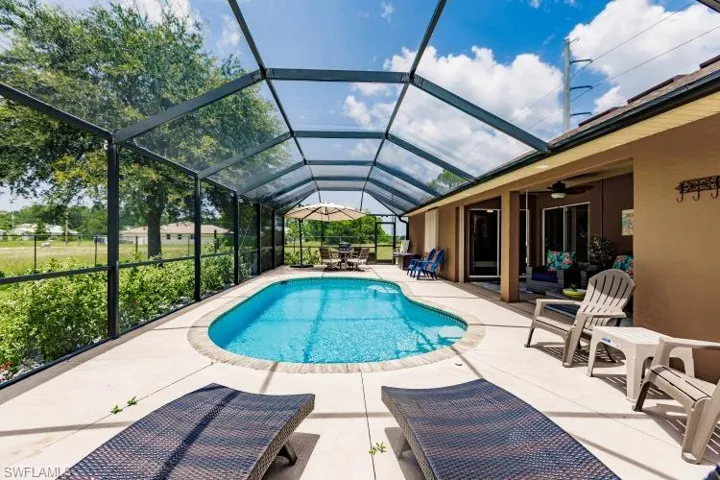 View of swimming pool with a lanai, ceiling fan, and a patio area
