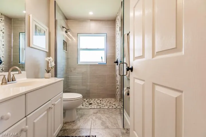 Bathroom with a tile shower, vanity, and toilet