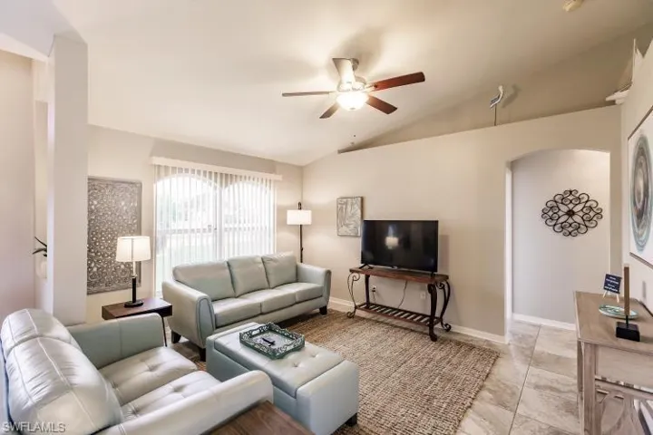 Tiled living room with vaulted ceiling and ceiling fan