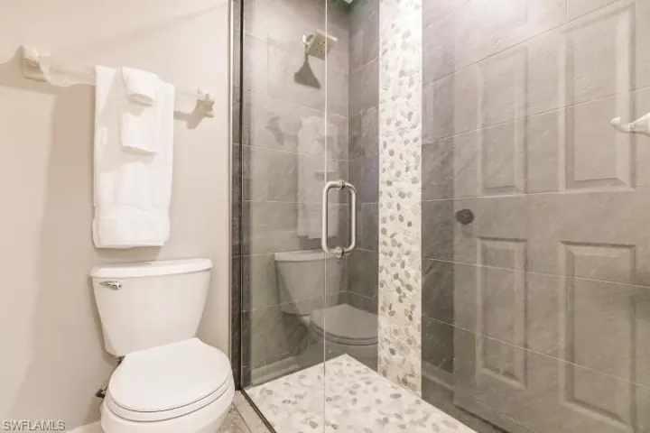 Bathroom featuring a shower with shower door and toilet