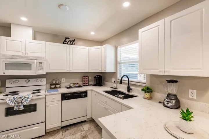 Kitchen featuring white cabinets, white appliances, and sink