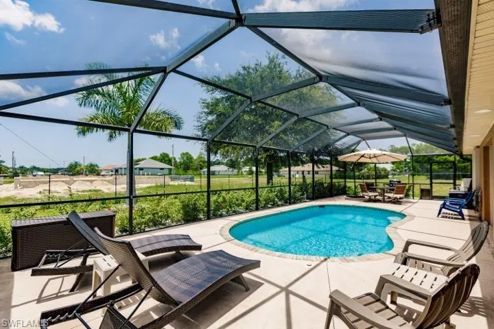 View of swimming pool featuring glass enclosure and a patio