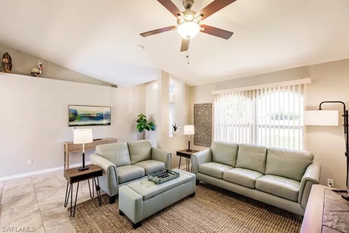 Tiled living room featuring ceiling fan and vaulted ceiling