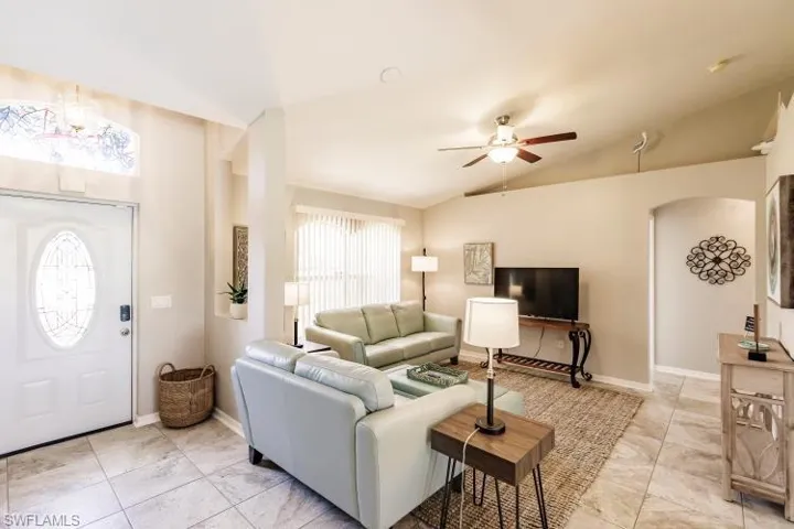 Tiled living room featuring ceiling fan, lofted ceiling, and a healthy amount of sunlight