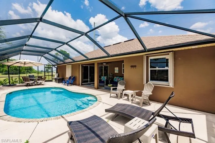 View of pool with glass enclosure and a patio