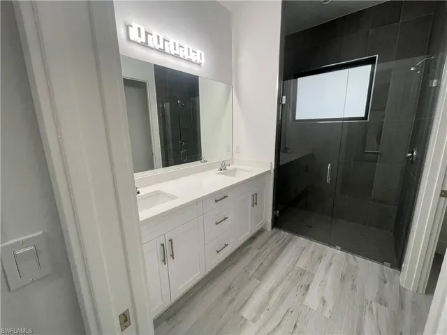 Bathroom with a stall shower, double vanity, and light wood-style floors