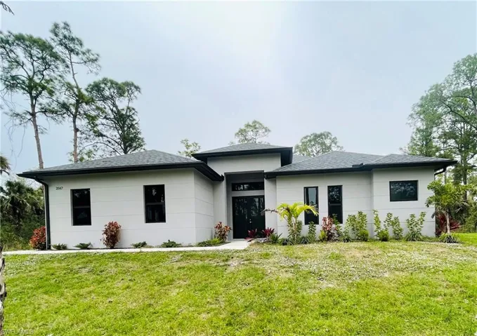 Prairie-style home with a front lawn and roof with shingles