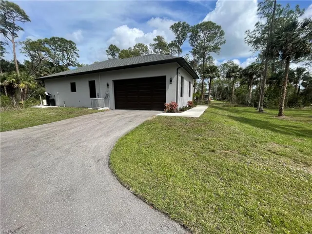View of front of property featuring stucco siding, an attached garage, a front lawn, and driveway