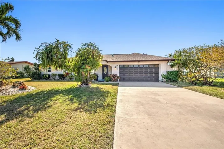 Ranch-style house featuring a front yard, a garage, concrete driveway, and stucco siding