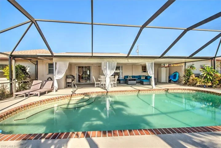 Outdoor pool featuring glass enclosure, a sunroom, outdoor lounge area, and a patio area