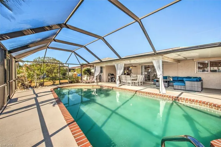 Swimming pool with a sunroom, a patio, glass enclosure, and an outdoor hangout area